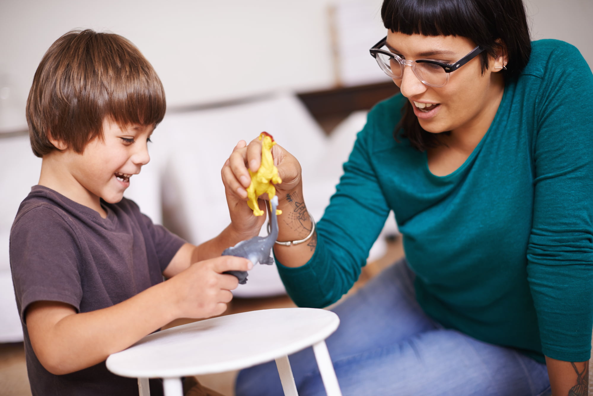 Therapist and child communicating while playing with dinosaur toys